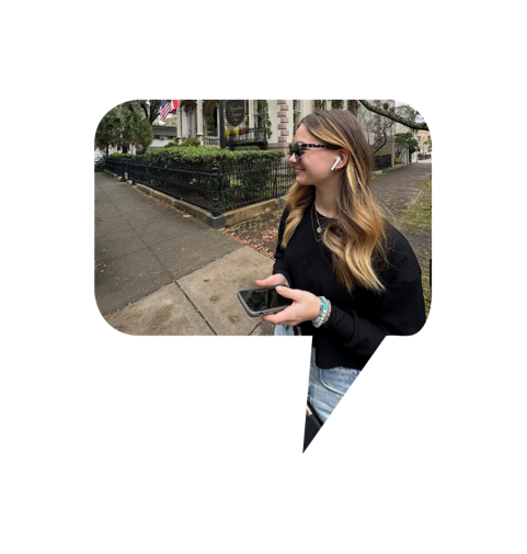 Young woman enjoying an audio tour while walking through a historic district, wearing wireless earbuds and holding a smartphone